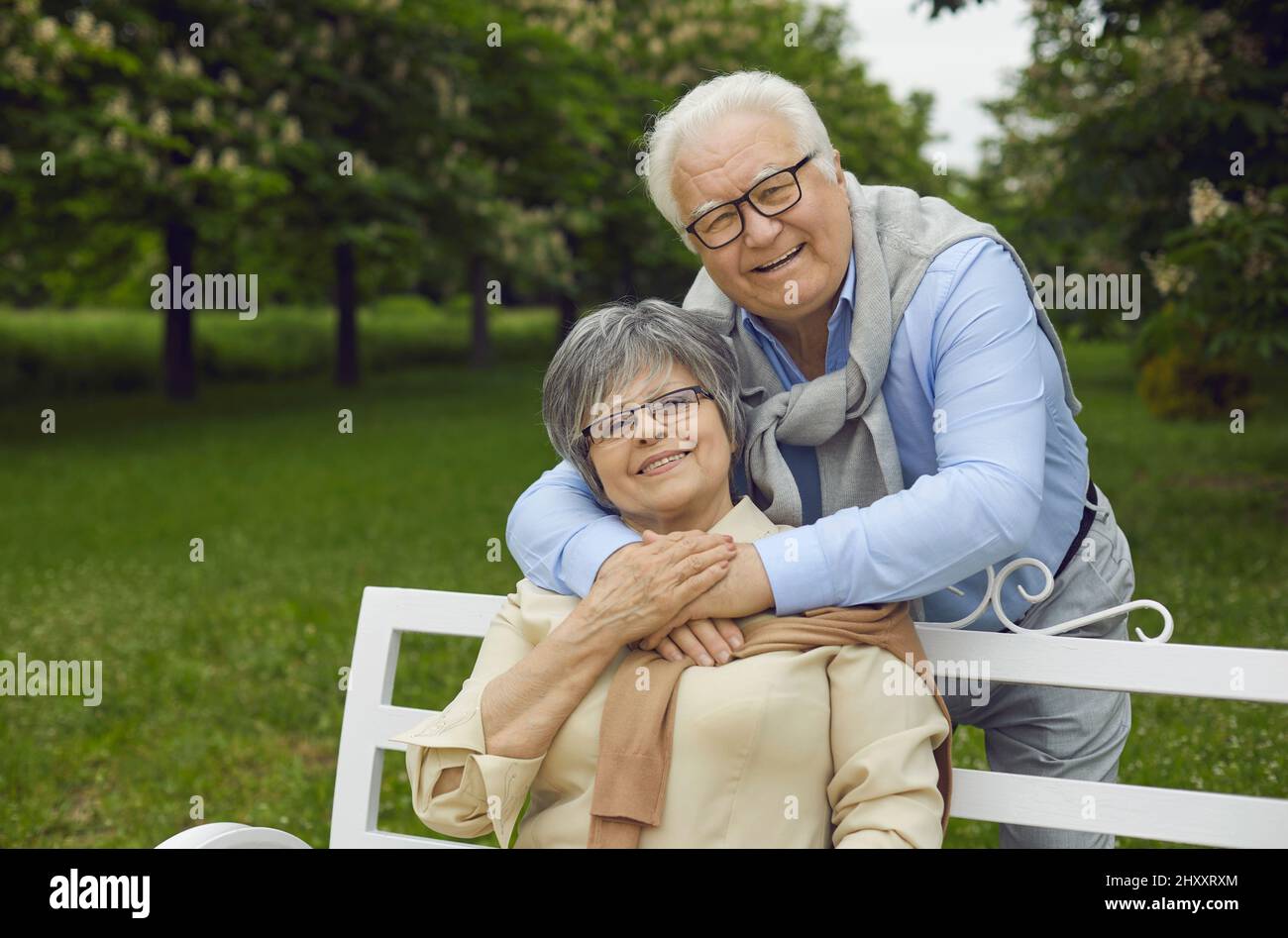 Ältere glückliche Männer und Frauen ruhen im Park auf einer Bank und atmen frische Luft ein Stockfoto
