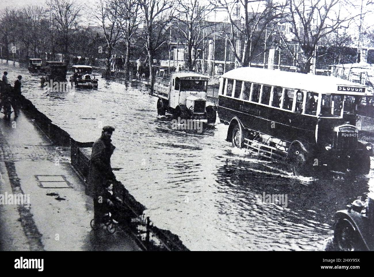 Ein Pressefoto aus den 1930er Jahren von Überschwemmungen auf der Great Bath Road in Maidenhead, Großbritannien. Der alte Bus fährt nach Slough Stockfoto