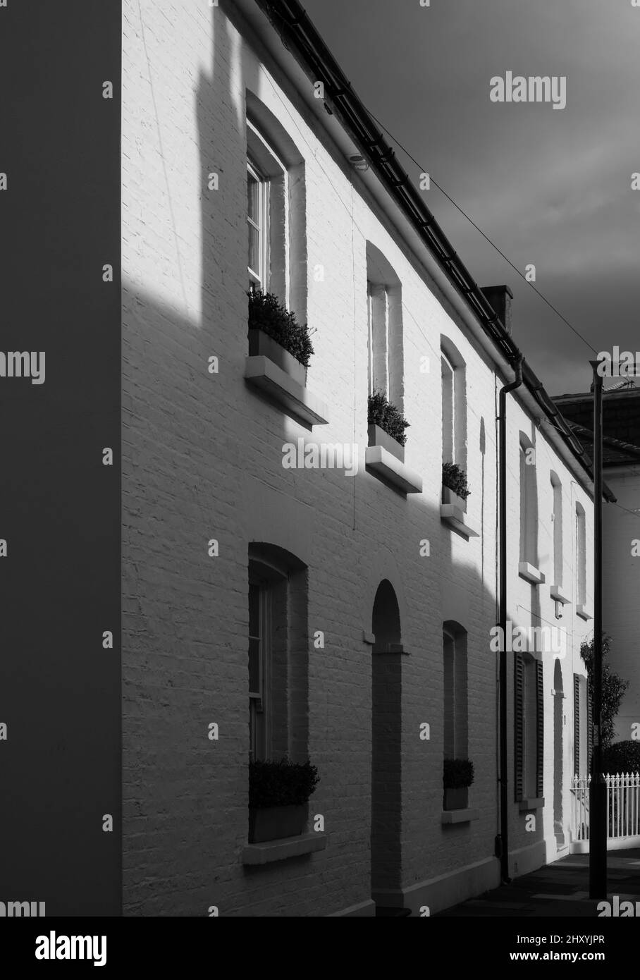 Reihe von Terrassenhäusern in Barnes, West-London, fotografiert am späten Nachmittag mit tiefen Schatten über der weißen Fassade. Stockfoto