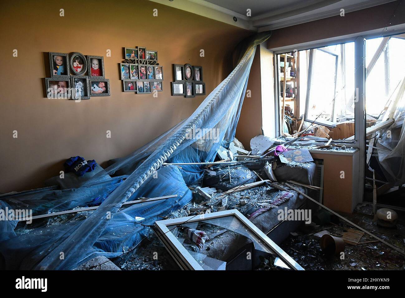 Kiew, Ukraine. 14. März 2022. Ein Wohnzimmer wird durch abgeschossene Raketenabschussstücke über dem Kiewer Stadtteil Oblon zerstört. Familienfotos hängen noch an der Wand, es ist nicht bekannt, ob die Familie vor dem Angriff geflohen war. Eine vom Luftangriffsverteidigungssystem abgeschossene Rakete traf ein Wohnhaus in Kiew, um einen Brand zu verursachen, einen zu töten und zwei weitere zu verletzen. Viele Einwohner Kiews sind aus dem Westen geflohen, um die bevorstehende Gewalt russischer Truppen zu vermeiden, die sich gegen die Stadt einlassen. Kredit: SOPA Images Limited/Alamy Live Nachrichten Stockfoto