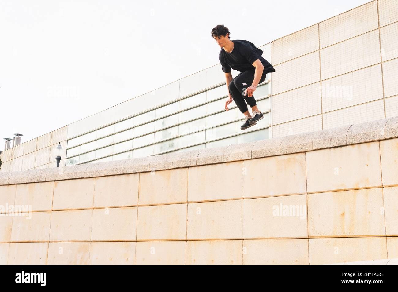 Niedriger Winkel der volle Länge Sportler Mann im Sport-Outfit tun Sprung über die Wand und Training Parkour Stunt Stockfoto