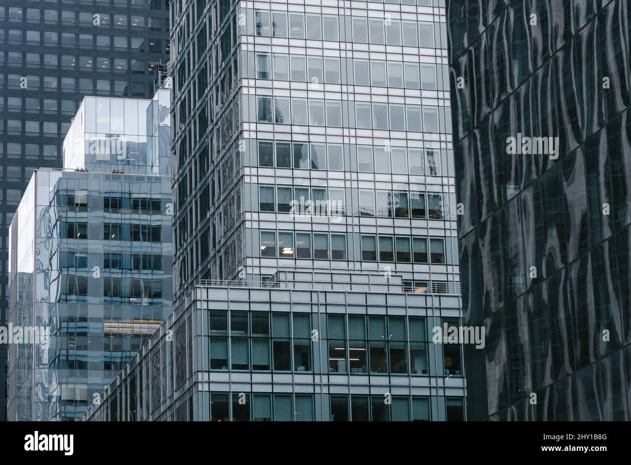 Von unten aus befinden sich moderne Hochhäuser mit gläsernen Spiegelwänden, die sich an der Straße der modernen Stadt befinden Stockfoto