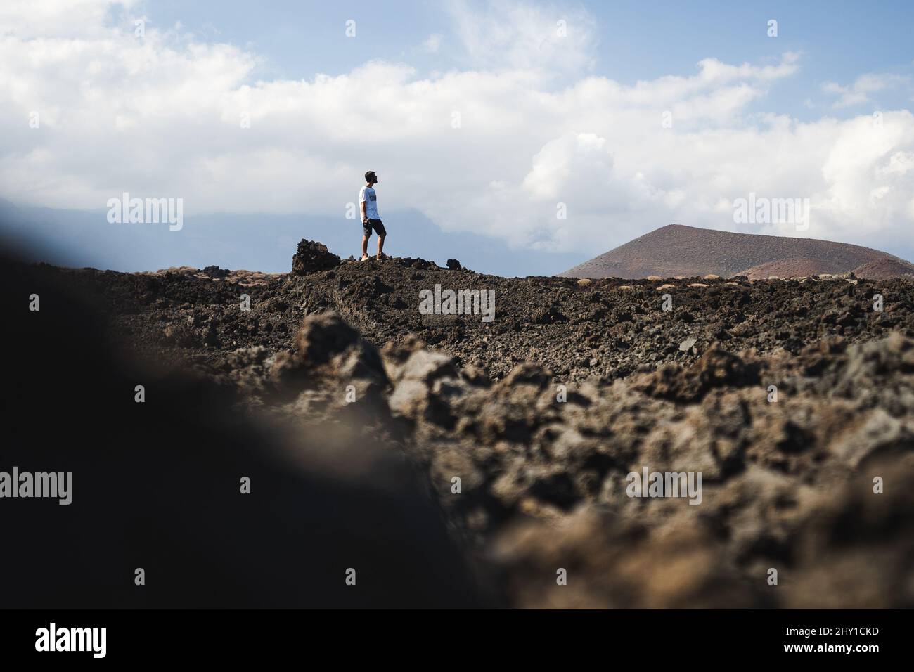 Seitenansicht eines anonymen männlichen Reisenden in Sonnenbrillen, der während des Sommerurlaubs in trockenem Gelände auf der vulkanischen Insel Teneriffa steht Stockfoto