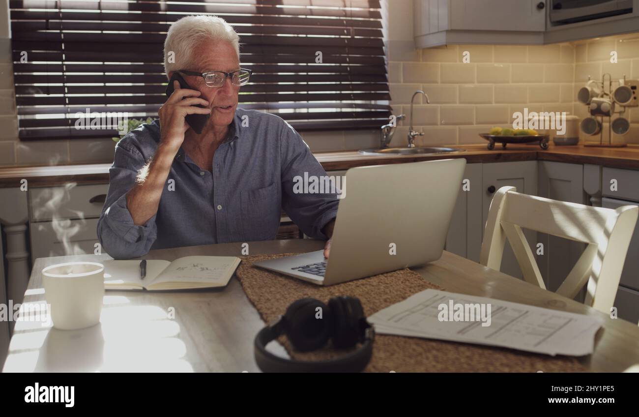 Das Alter hat mich nicht davon abgehalten zu arbeiten. Aufnahme eines älteren Mannes, der allein in der Küche sitzt und Technologie verwendet, um von zu Hause aus zu arbeiten. Stockfoto