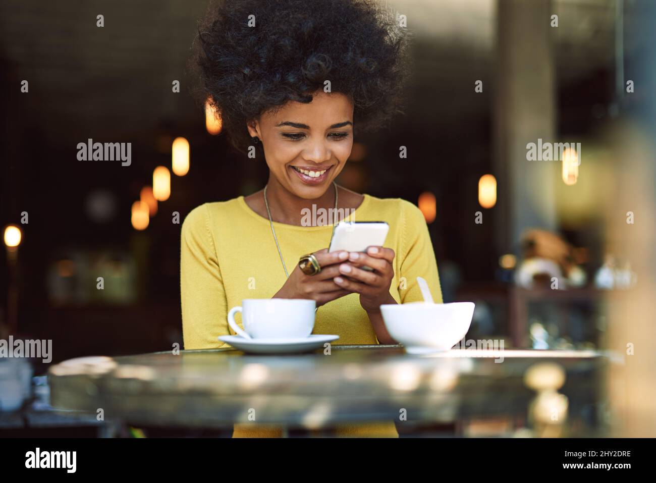 Kurztext wird gesendet. Aufnahme einer jungen Frau, die in einem Café auf einem Handy SMS schreibt. Stockfoto