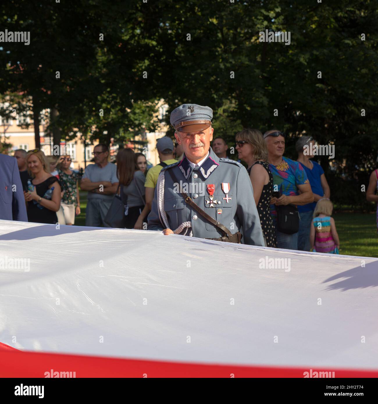 Suwalki, Polen - 24. August 2019: Militärveteran in Militäruniform mit großer polnischer Flagge zur Feier des 100. Jahrestages der Befreiung Stockfoto