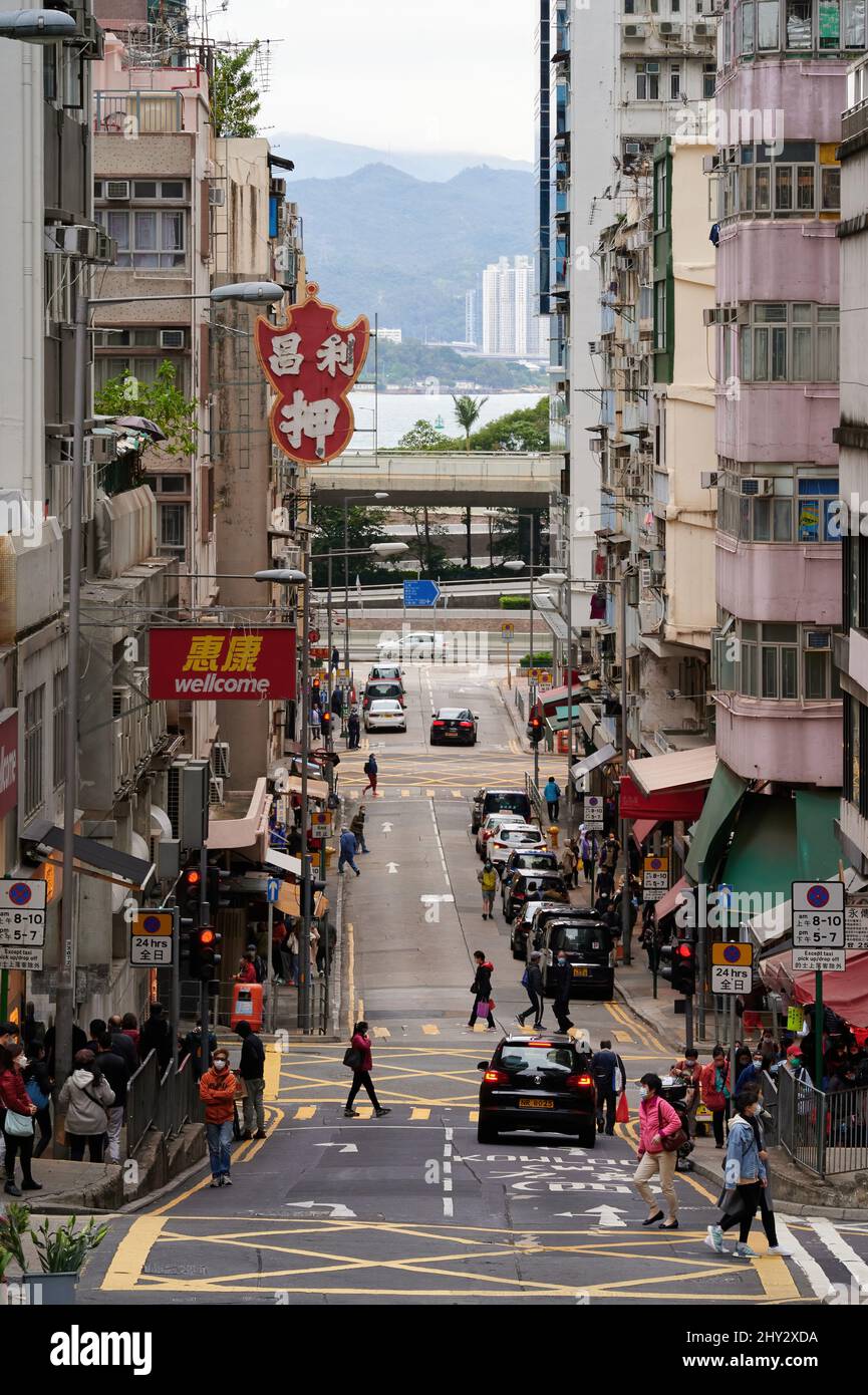 Vertikale Aufnahme einer belebten Straße mit Spaziergängen und Hochhäusern in Sheung Wan, Hongkong Stockfoto