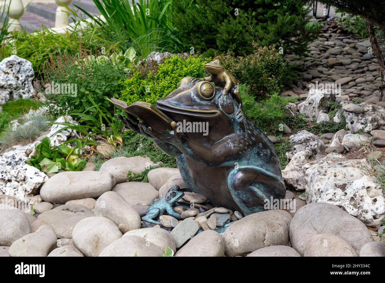 KHARKIV, UKRAINE - 3. AUGUST 2021: Dies ist eine Figur eines Leserfrosches mit Babyfröschen am Ufer eines künstlichen Teiches im Kulturpark der Stadt Stockfoto