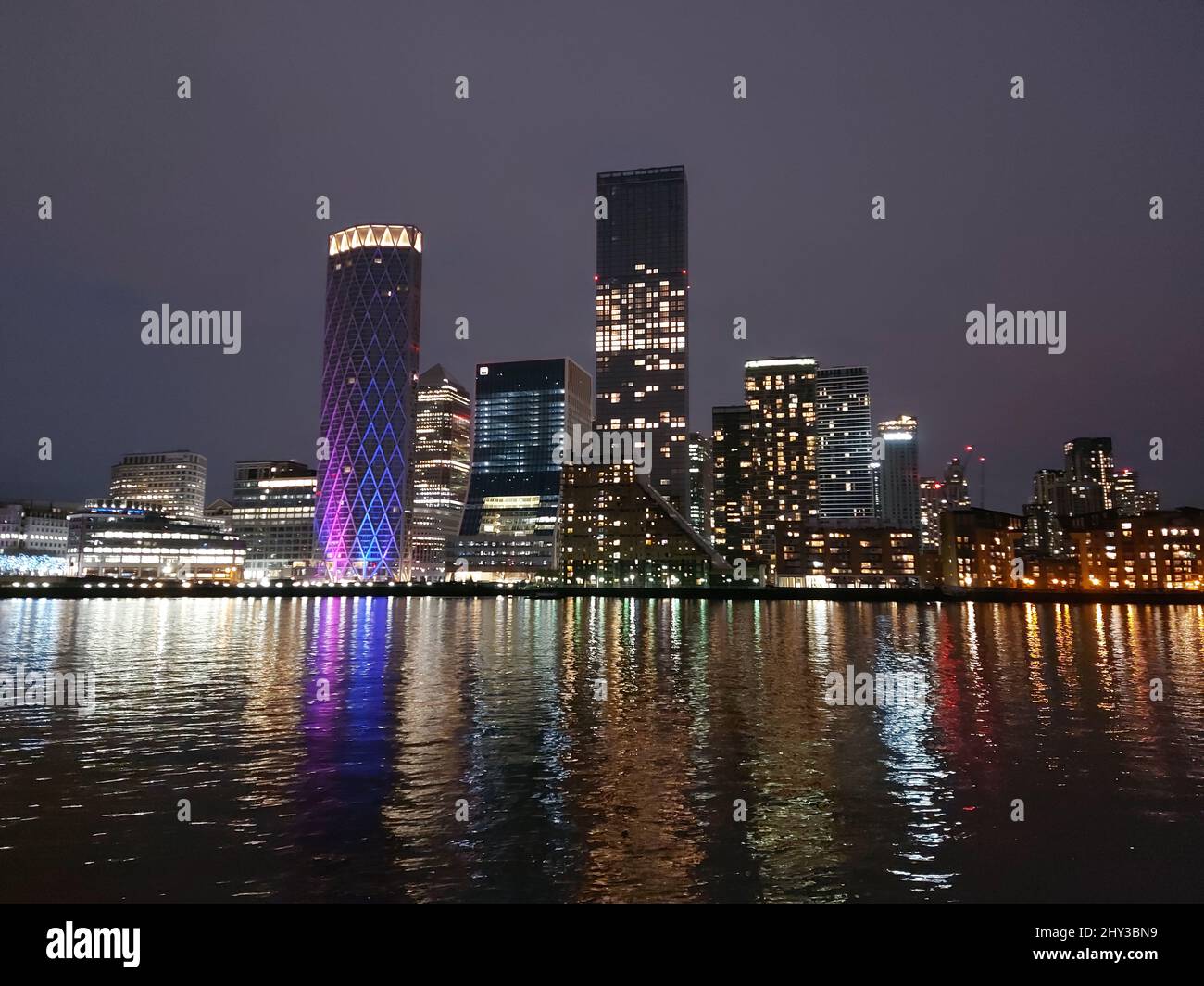 Blick auf die Ufergebäude von Canary Wharf, die sich in der Nacht auf der Themse spiegeln Stockfoto