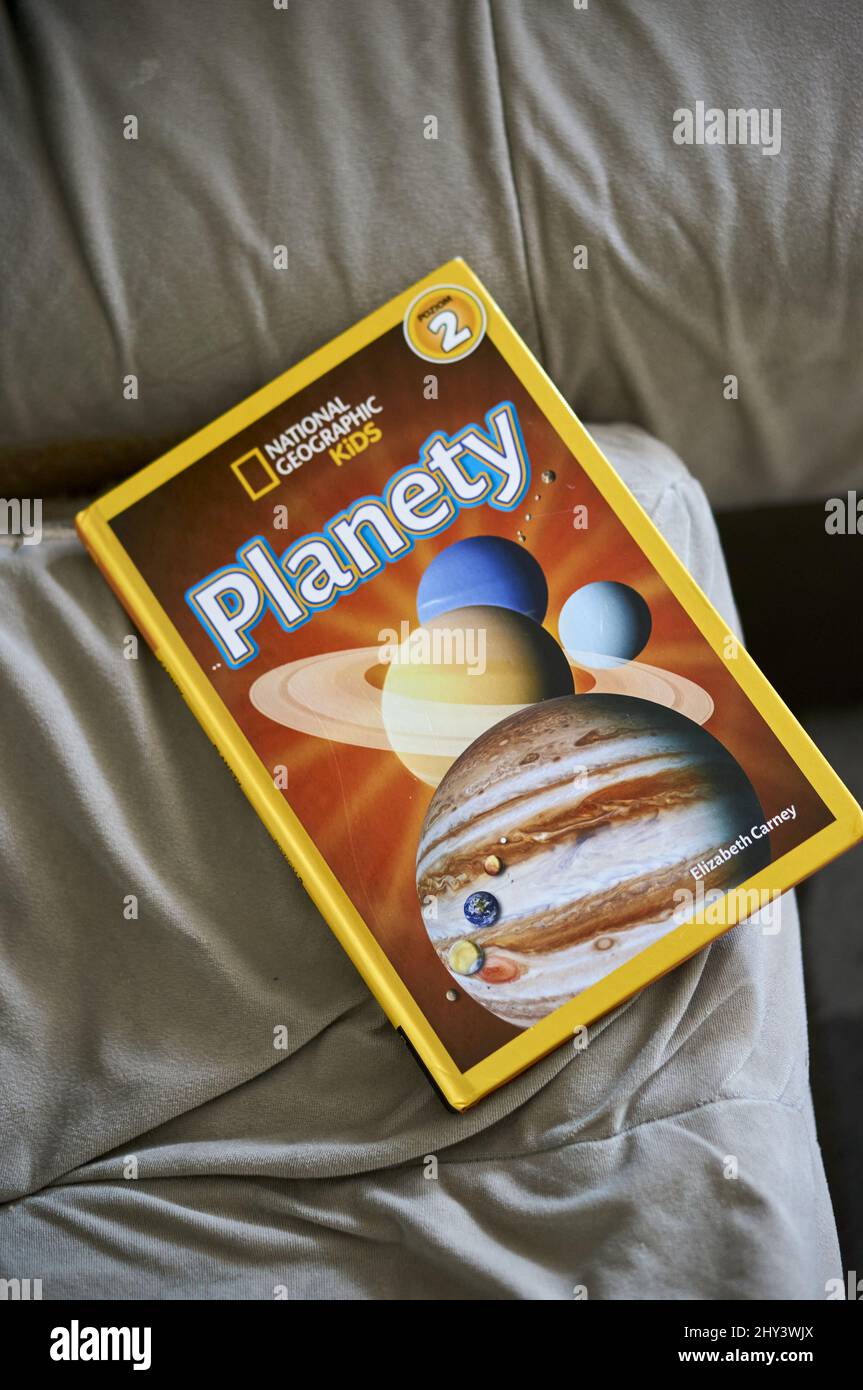 Vertikale Nahaufnahme des polnischen National Geographic-Buches über Planeten für Kinder, die auf einem Sofa liegen. Stockfoto