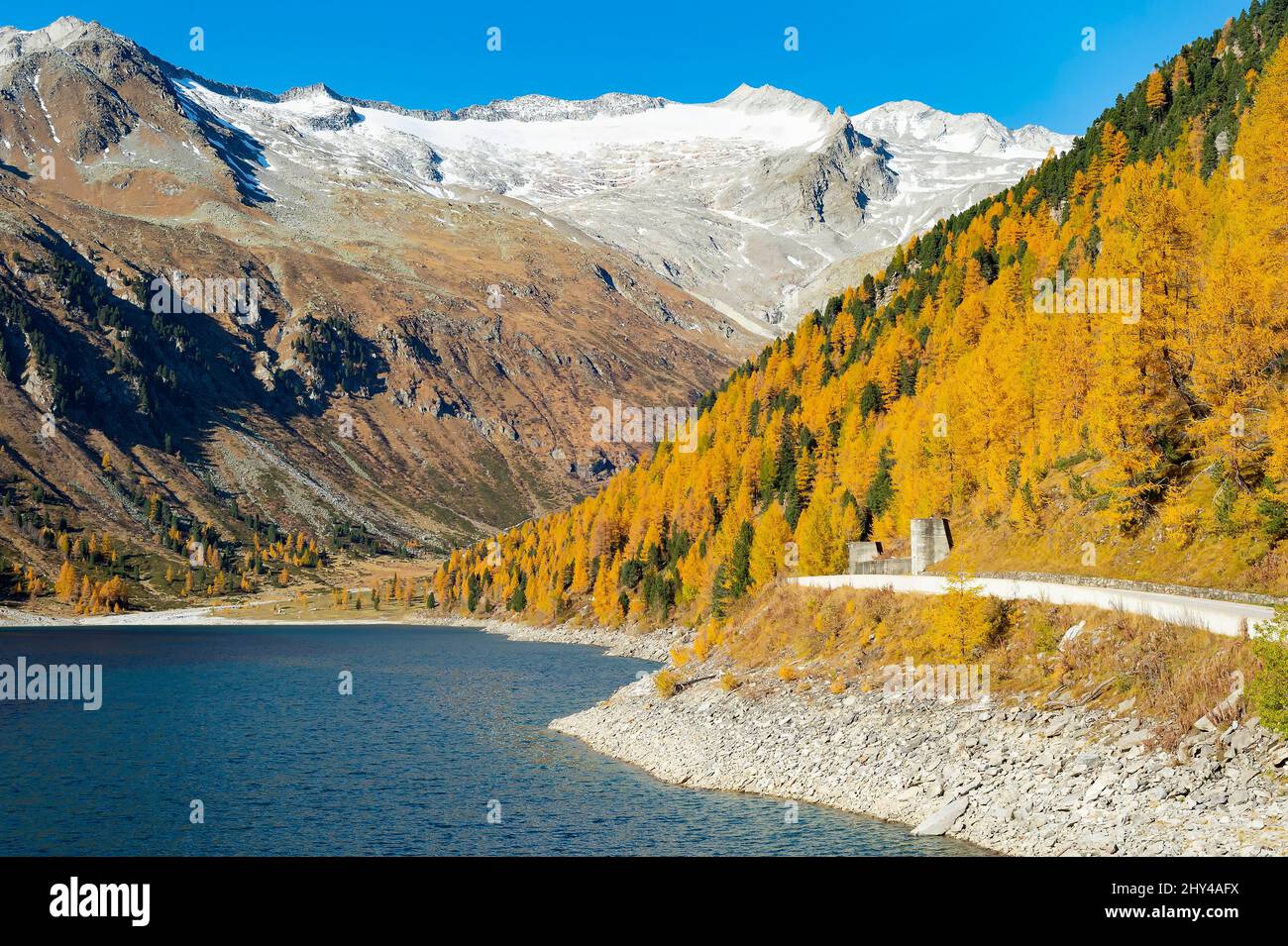 Malerische Bergstraße in den Alpen, blauer See, mit Wald bedeckte Hänge, schneebedeckte Berggipfel in hellen sonnigen Herbsttag, Österreich Stockfoto