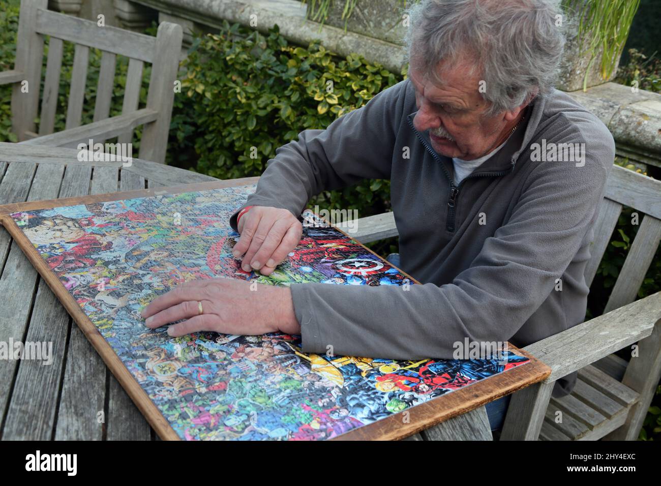 Mann macht eine Marvel 1000 Stück unmöglich Puzzle im Garten Stockfoto