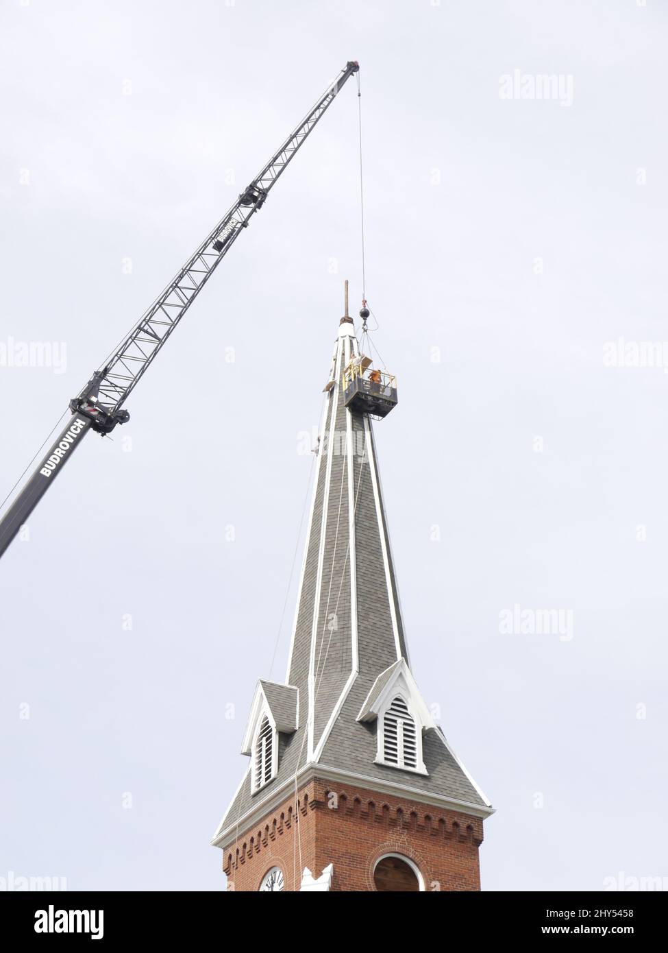 Baukran und Arbeiter reparieren einen Kirchturm an einer Kirche in Missouri Stockfoto