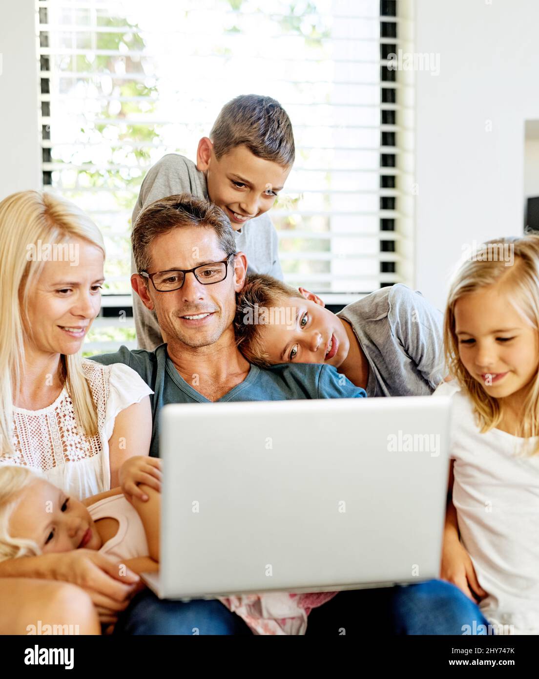 Ihre Kinder in die Online-Welt einführen. Aufnahme einer Familie, die zu Hause einen Laptop benutzt. Stockfoto