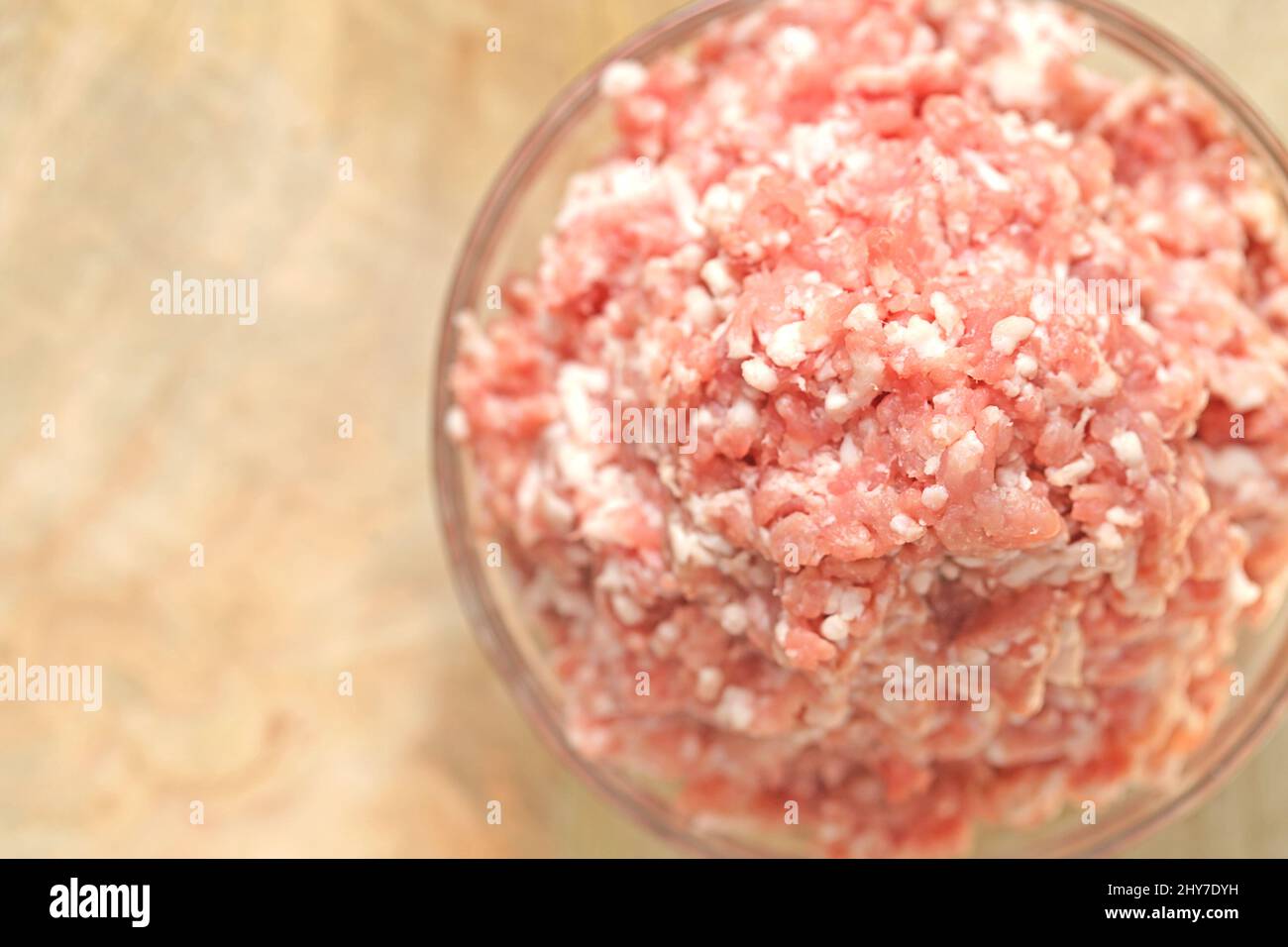 Hackfleisch aus Schweinefleisch. Frisches Hackfleisch aus nächster Nähe in einer transparenten Tasse auf einem Holztisch. Fleischerzeugnisse Stockfoto