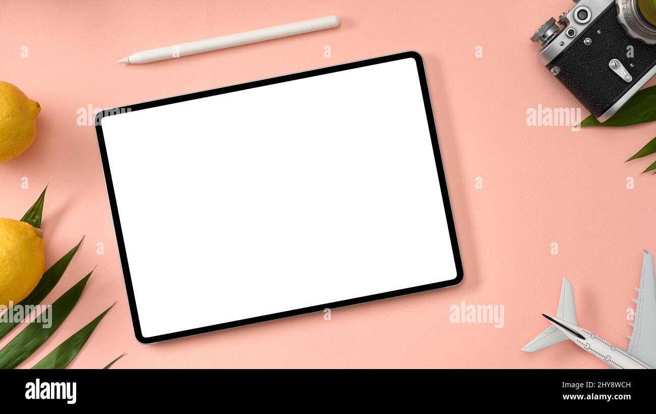 Tablet-Computer mit weißem Bildschirm-Mockup mit Stylus-Stift, Kamera, Flugzeug, Zitronen und Palmblatt auf rosa Hintergrund. Sommer-Hintergrund mit Tablet-Mockup c Stockfoto