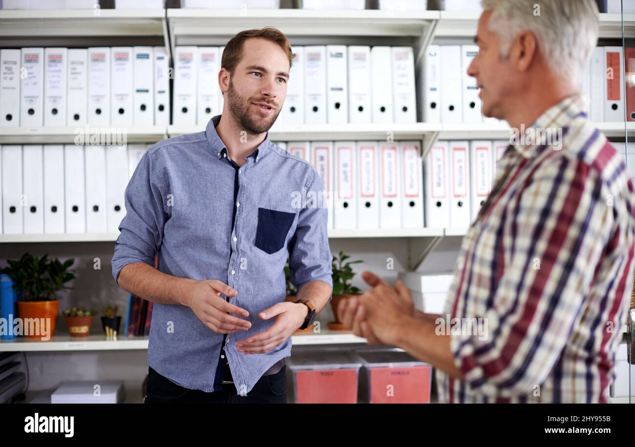 Ideen für ihr neuestes Projekt austauschen. Aufnahme von zwei männlichen Büromitarbeitern, die eine Diskussion führen. Stockfoto