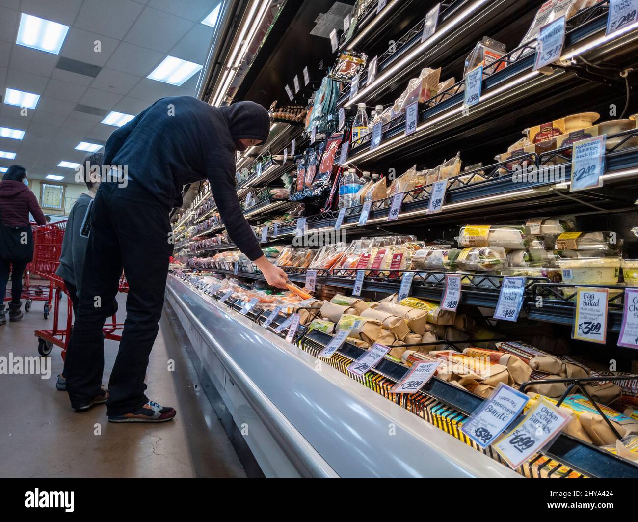 Kirkland, WA USA - ca. Februar 2022: Kaukasischer Mann in einem Kapuzenpullover, der im Delikatessengeschäft und in einem Trade Joe's Lebensmittelgeschäft zubereitete Lebensmittel einkauft. Stockfoto