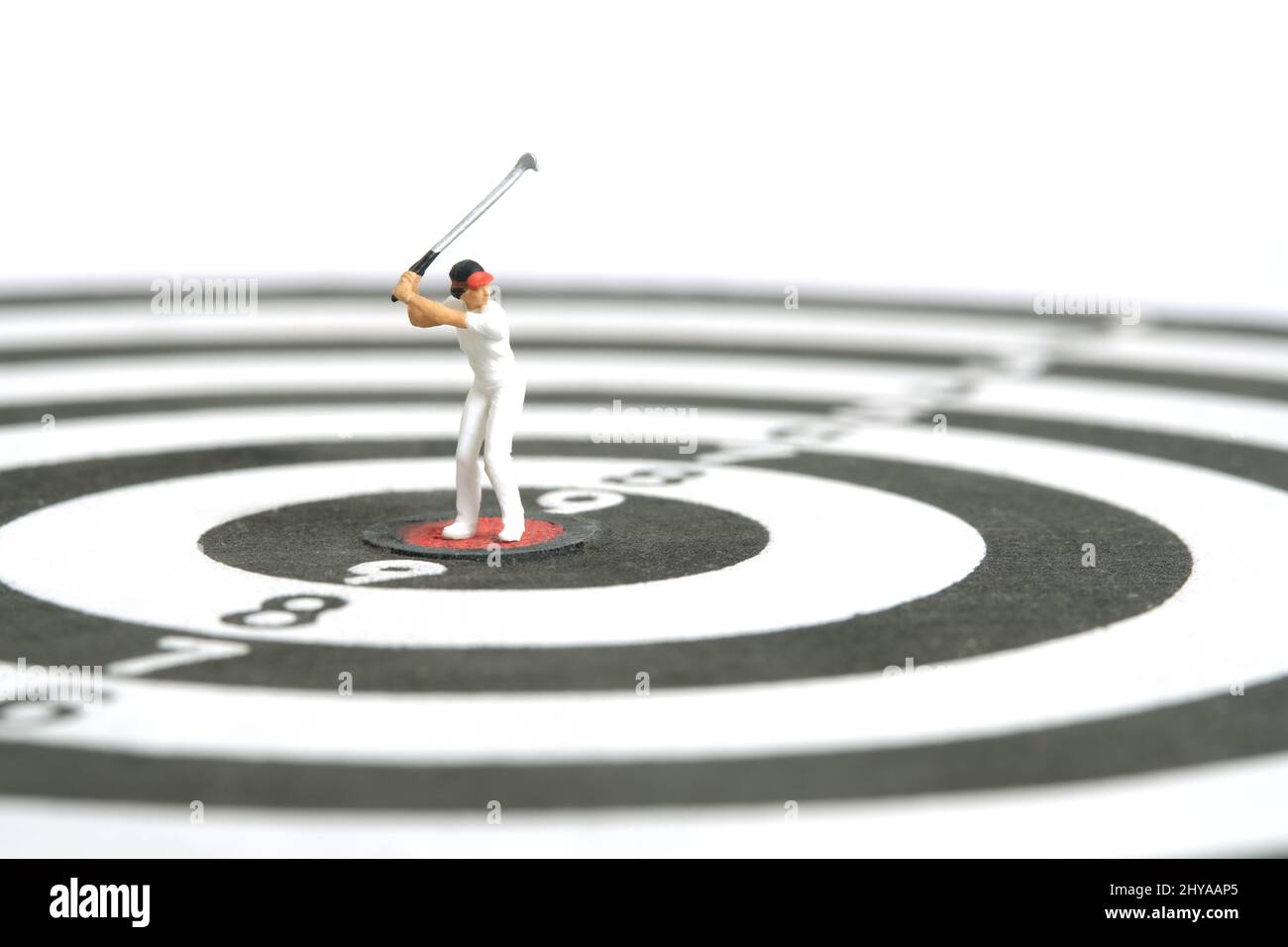 Miniatur Menschen Spielzeug Figur Fotografie. Ein Golfermädchen, das in der Mitte über der Dartscheibe steht, isoliert auf weißem Hintergrund. Bildfoto Stockfoto