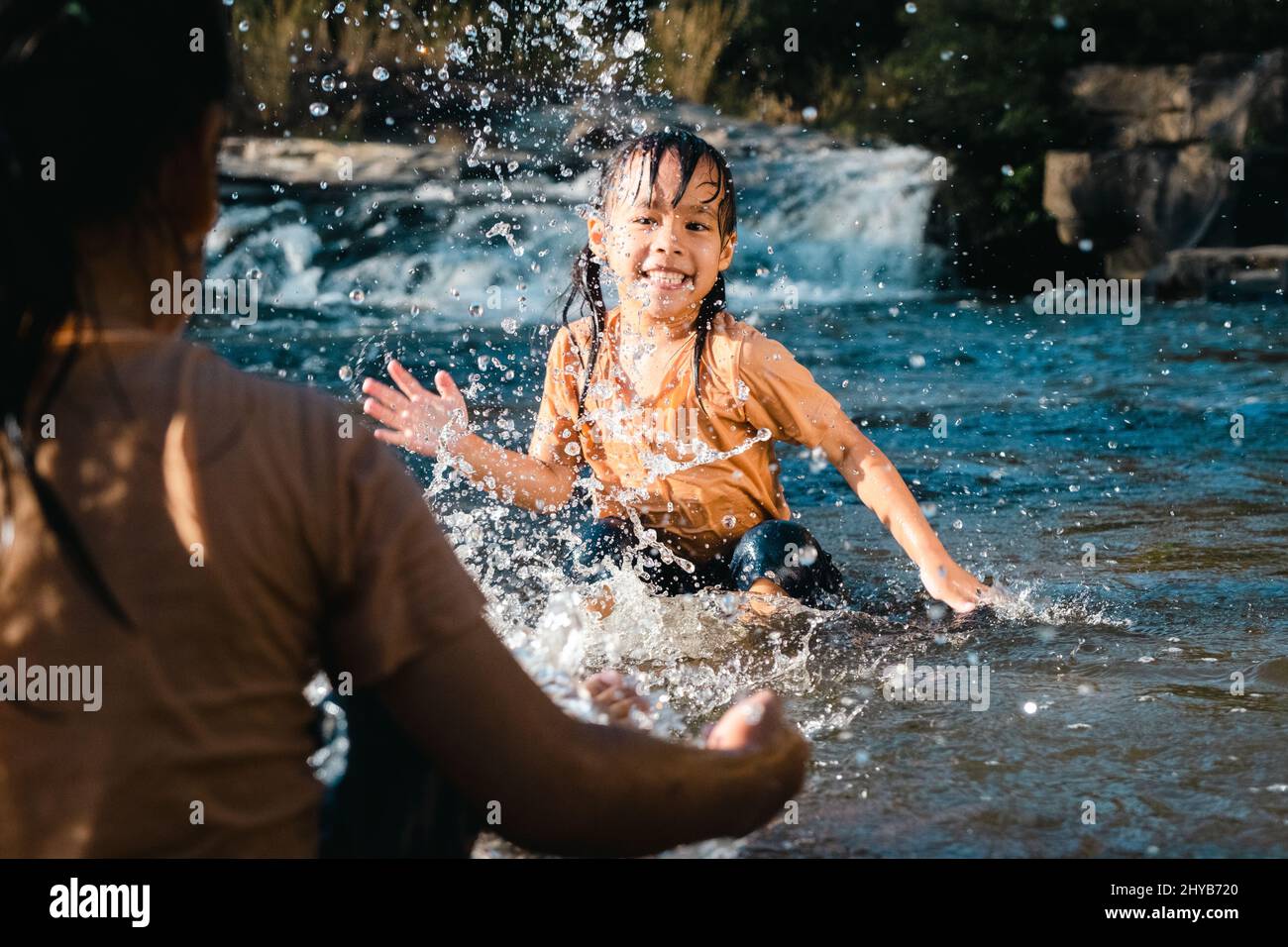 Asiatische kleine Mädchen spielt im Wald Strom mit ihrer Schwester. Aktive Erholung mit Kindern auf dem Fluss im Sommer. Stockfoto