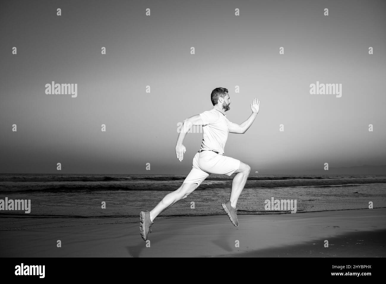 Mann, der bei Sonnenuntergang am Strand läuft. Athletischer junger Mann, der in der Natur läuft. Stockfoto
