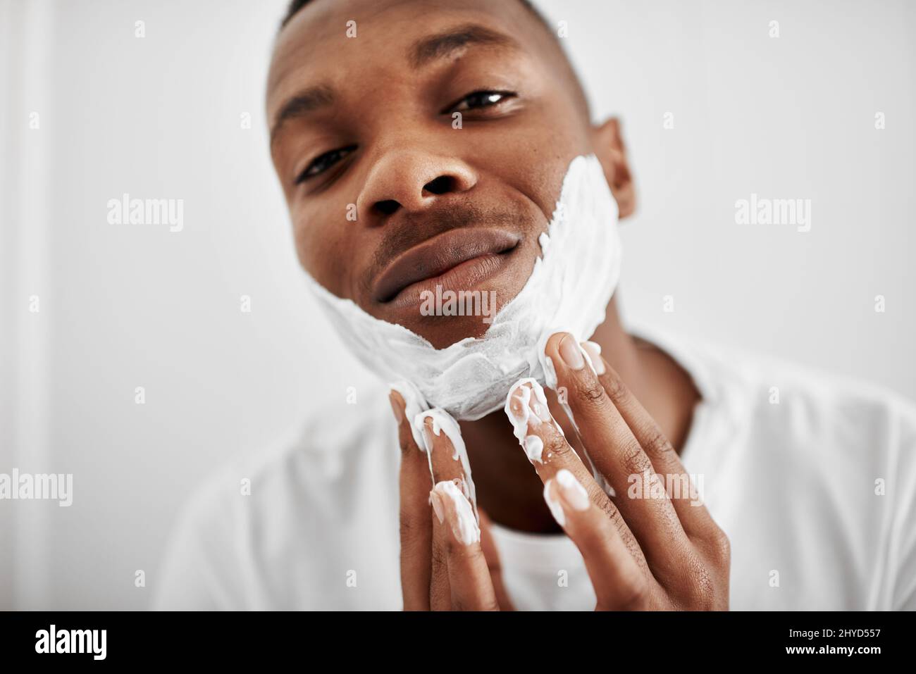 Ich rasur es lieber alle. Kurzer Schuss eines jungen Mannes, der Rasierschaum auf sein Gesicht auftragen soll. Stockfoto