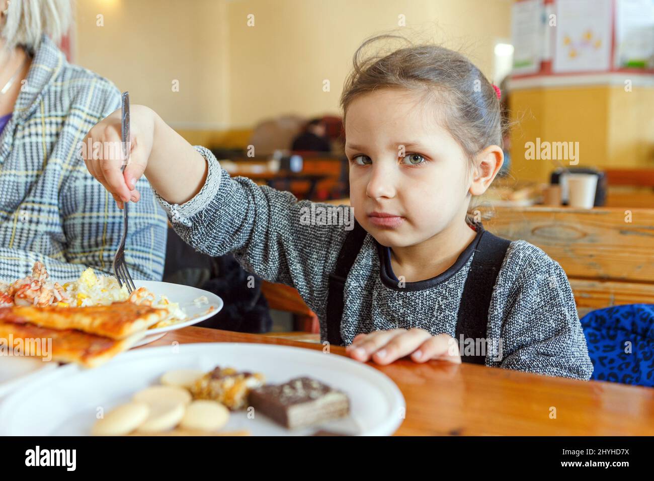 USCHHOROD, UKRAINE - 14. MÄRZ 2022 - Ein Mädchen isst in einem Restaurant, das Binnenvertriebenen, die vor der russischen Invasion fliehen, kostenlose Mahlzeiten anbietet, Stockfoto