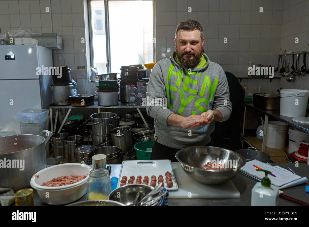 USCHHOROD, UKRAINE - 14. MÄRZ 2022 - Ein Freiwilliger rollt Fleischbällchen in einem Restaurant, das kostenlose Mahlzeiten für Binnenvertriebene anbietet, die aus dem Ru fliehen Stockfoto