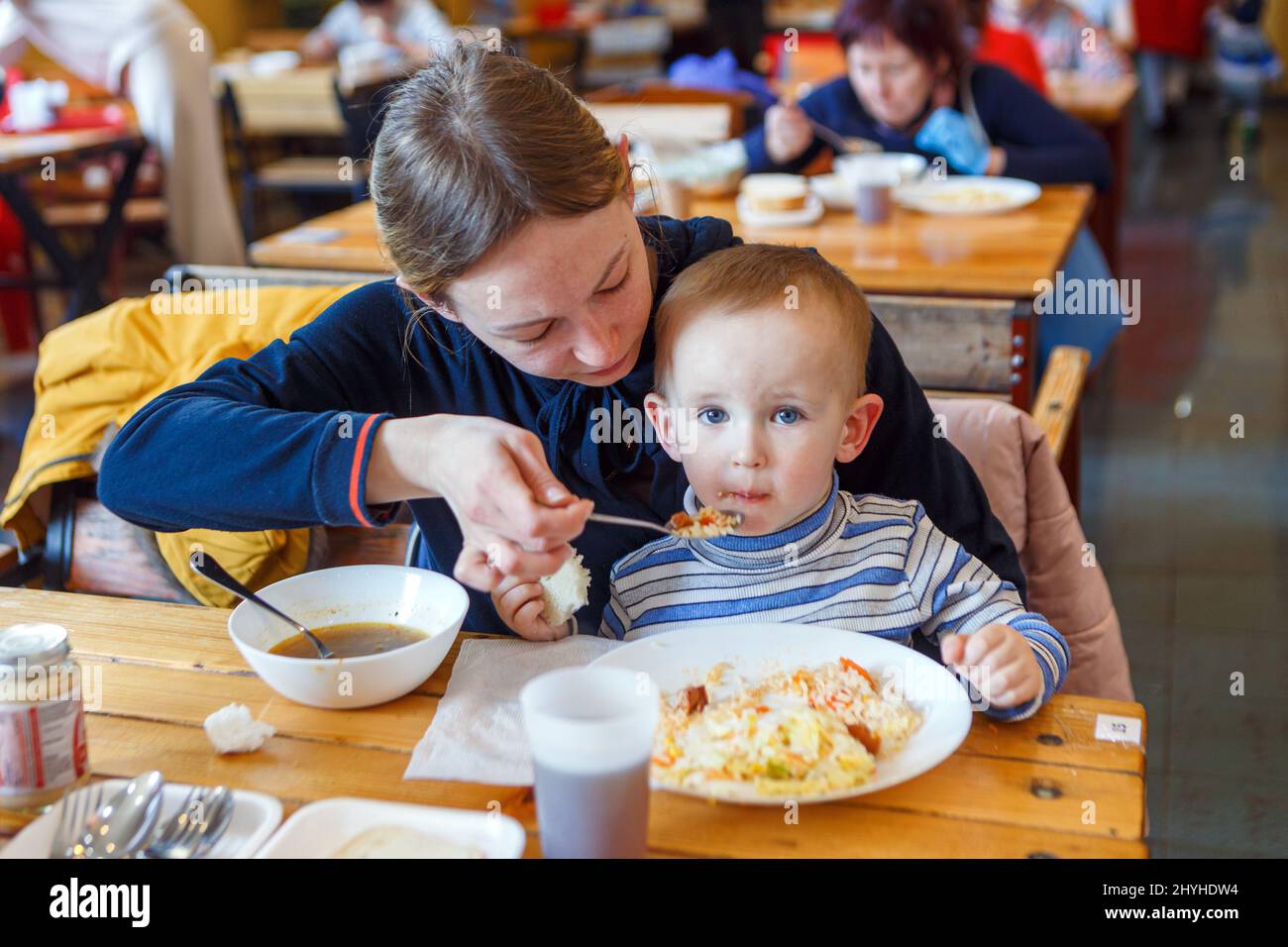 UZHHOROD, UKRAINE - 14. MÄRZ 2022 - Eine Frau füttert einen Jungen in einem Restaurant, das Binnenvertriebenen, die vor den Russi fliehen, kostenlose Mahlzeiten anbietet Stockfoto