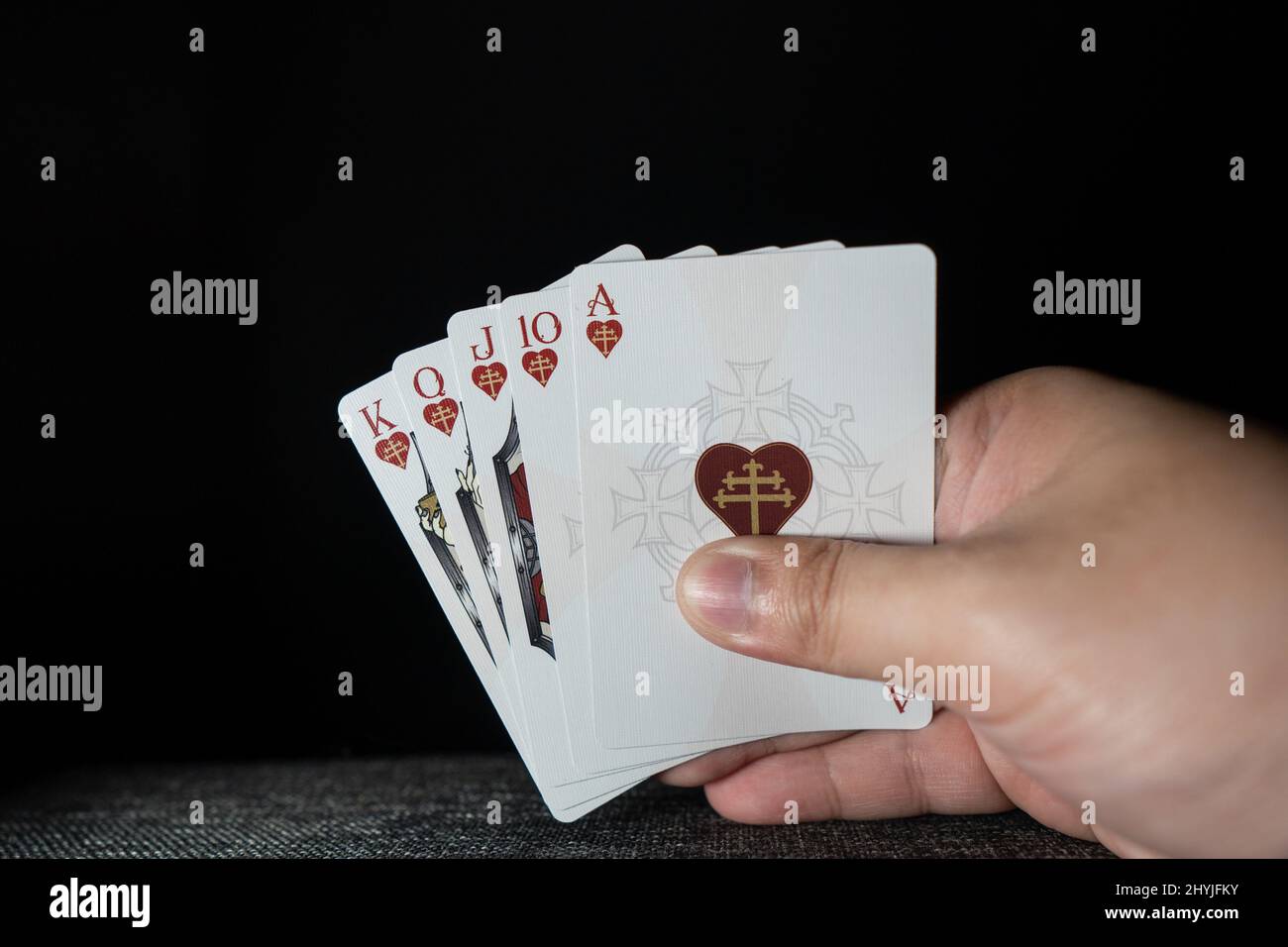 Flush Royal Herzen in einer Hand vor einem schwarzen Hintergrund Stockfoto