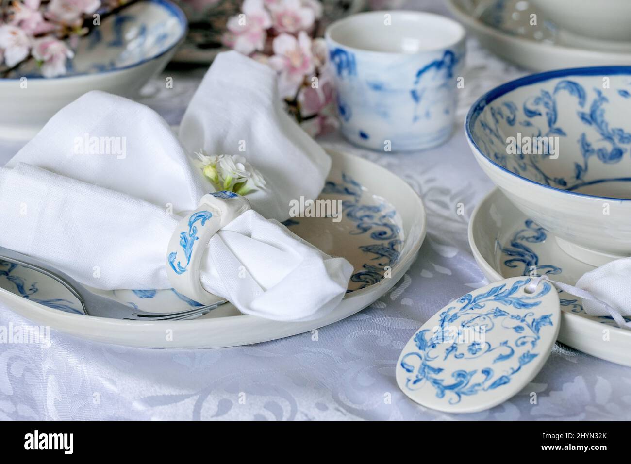 Elegantes Ostertischdekor mit leerem Meeresornament bemalten Porzellangeschirr, Tellern und Schüsseln, Ostereier-Dekorationen auf weißer Tischdecke. Ea Stockfoto