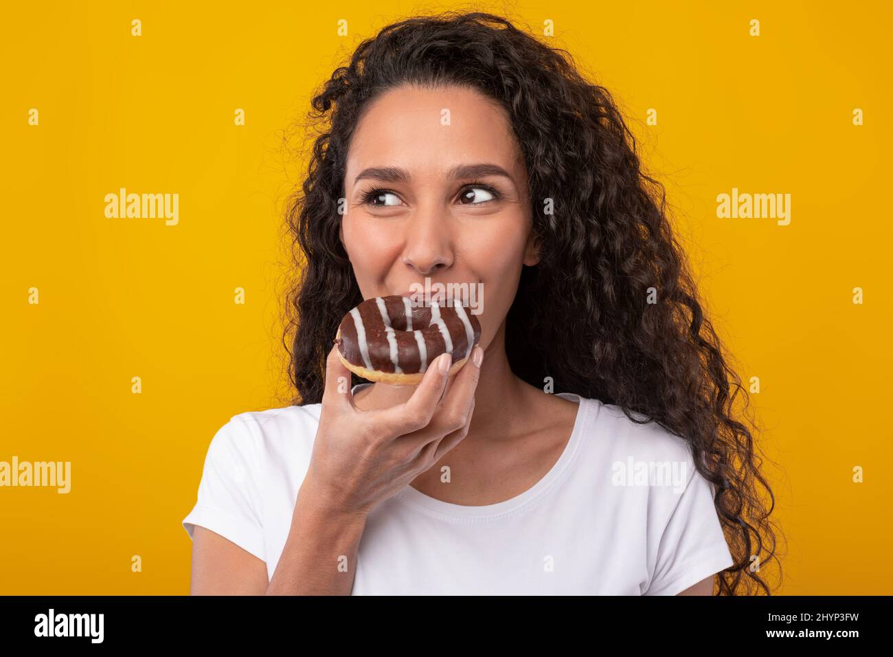 Lustige Latin Lady Holding Donut Beißkuchen Im Studio Stockfoto