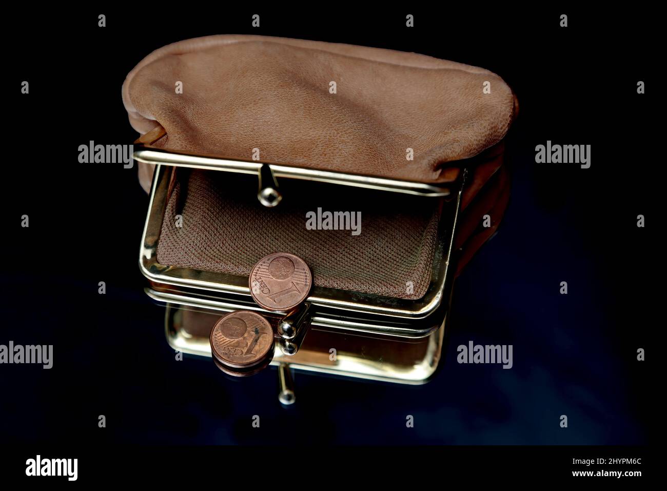 Eine Geldbörse und zwei 1-Cent-Münzen mit schwarzem Hintergrund Stockfoto
