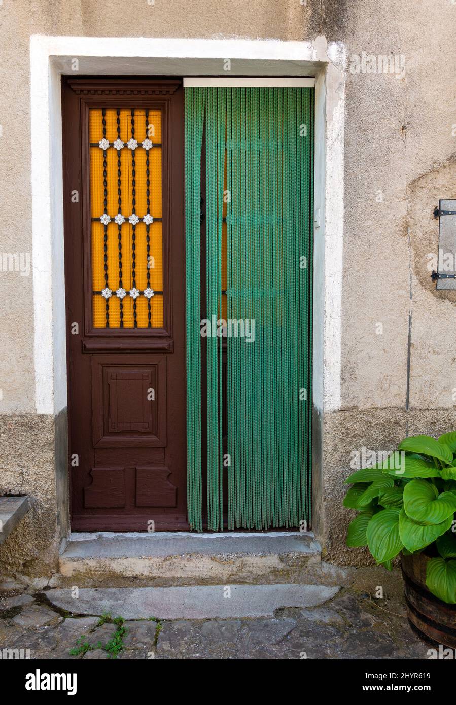 Die spanische Tür zeigt eine Holztür mit grünem Türvorhang und orangefarbenen Fensterläden Stockfoto
