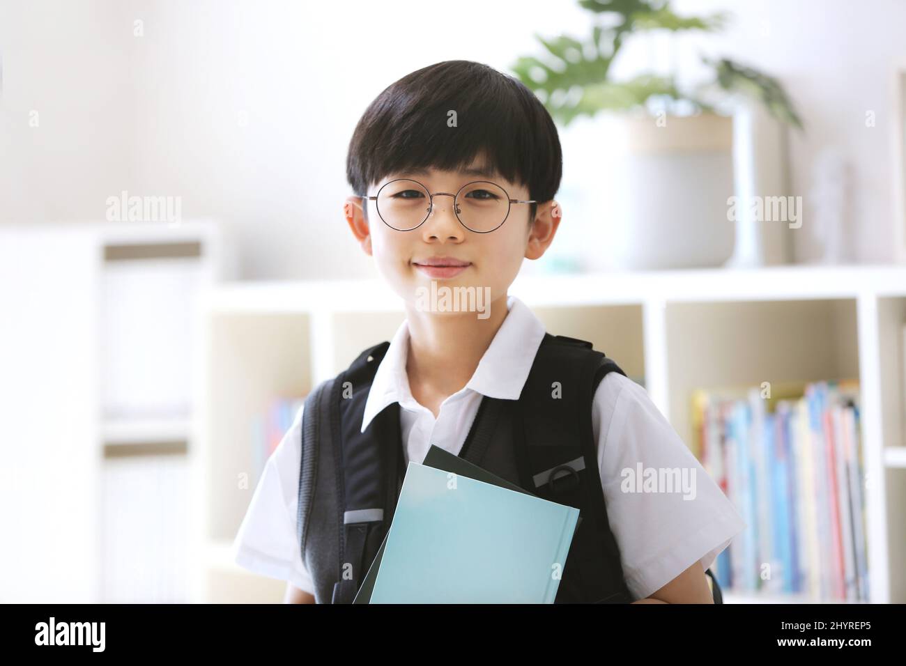 Abschluss, Zulassung und neues Semester Ein süßer und intelligenter Junge mit Rucksack und lächelndem Lächeln geht mit einem Buch zur Schule. Stockfoto