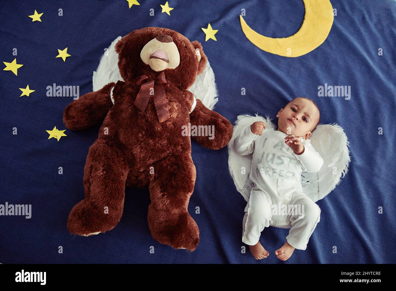 Babys sind Engel, die vom Himmel gesandt wurden. Konzeptaufnahme eines entzückenden Jungen und eines Teddybären mit Engelsflügeln gegen eine imaginäre Nachtzeit Stockfoto