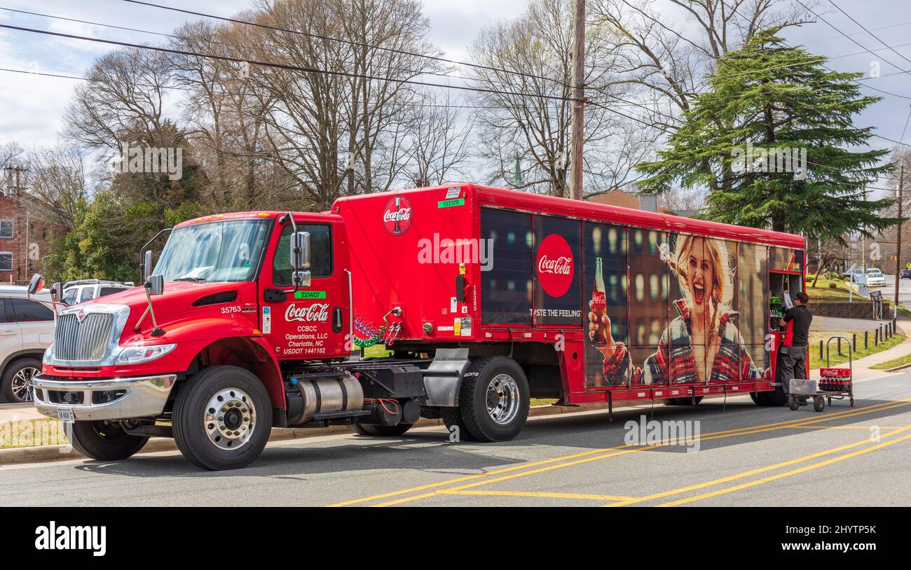 BELMONT, NC, USA-8. MÄRZ 2022: Farbenprächtiger roter Coca-Cola-Lieferwagen auf der Straße parkariert, mit Entladen des Lieferfahrers. Werbefoto der Frau. Stockfoto
