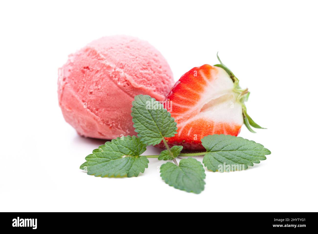Eine Kugel Stawberry-Eis, verziert mit Minzblättern und Erdbeeren Stockfoto