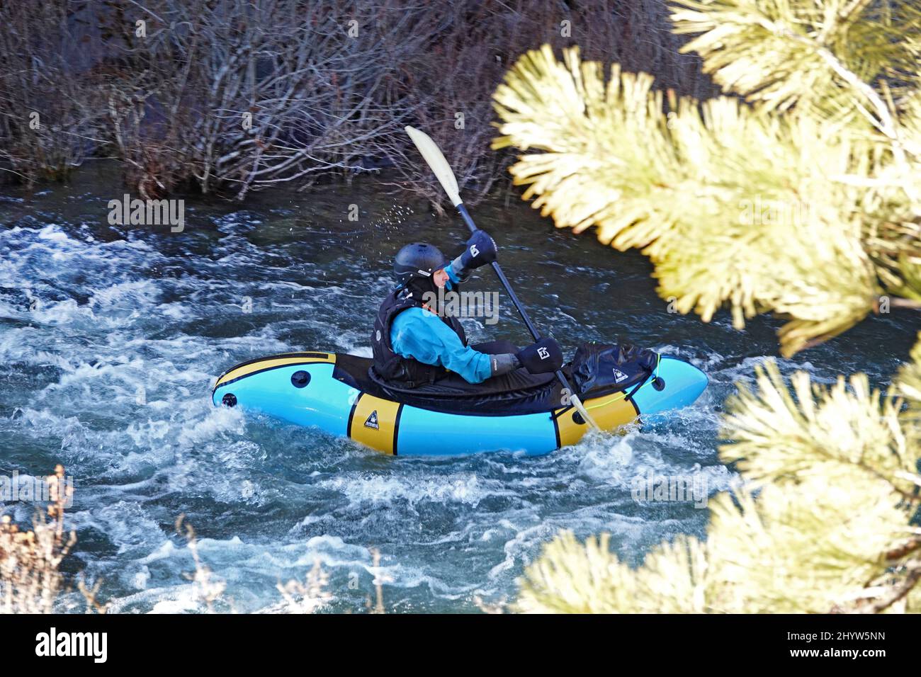 Ein Mann in einem trockenen Anzug, um ihn vor dem kalten Kajak auf dem Deschutes River in Oregon in einem kleinen Kajak zu schützen. Stockfoto