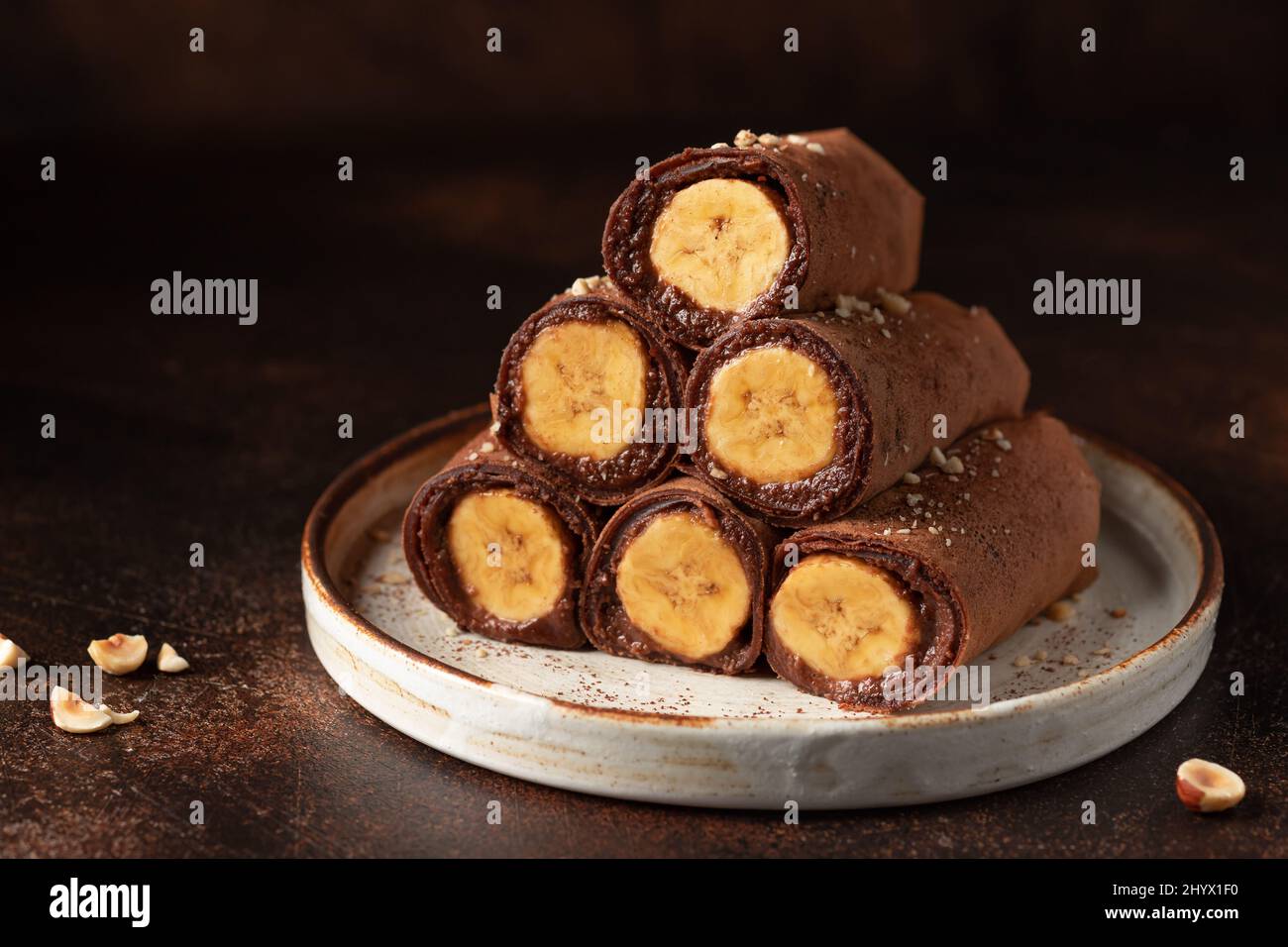 Mit Bananen gefüllte Schokoladencrepes auf dunklem Hintergrund Stockfoto