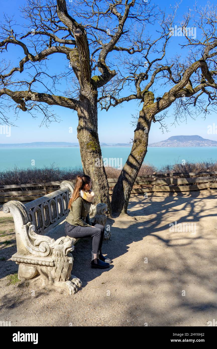Wunderschöne balaton-Landschaft in Fonyod Ungarn mit dekorierter Steinbank und dem badacsony-Hügel im Hintergrund mit Touristenfrau Stockfoto