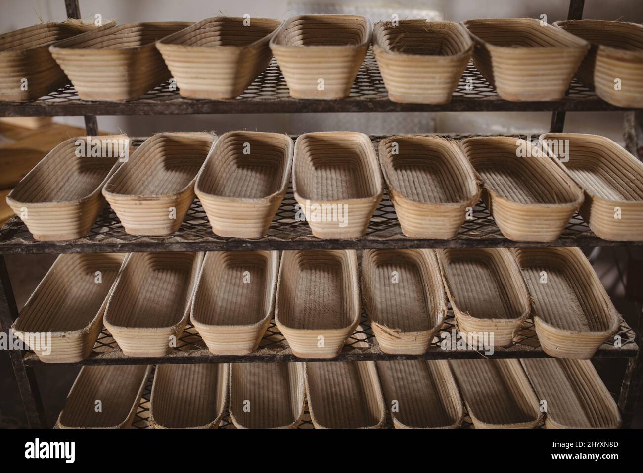 Vollbildaufnahme der Korbbrotkörbe, die nebeneinander auf dem Regal in der Bäckerei angeordnet sind Stockfoto