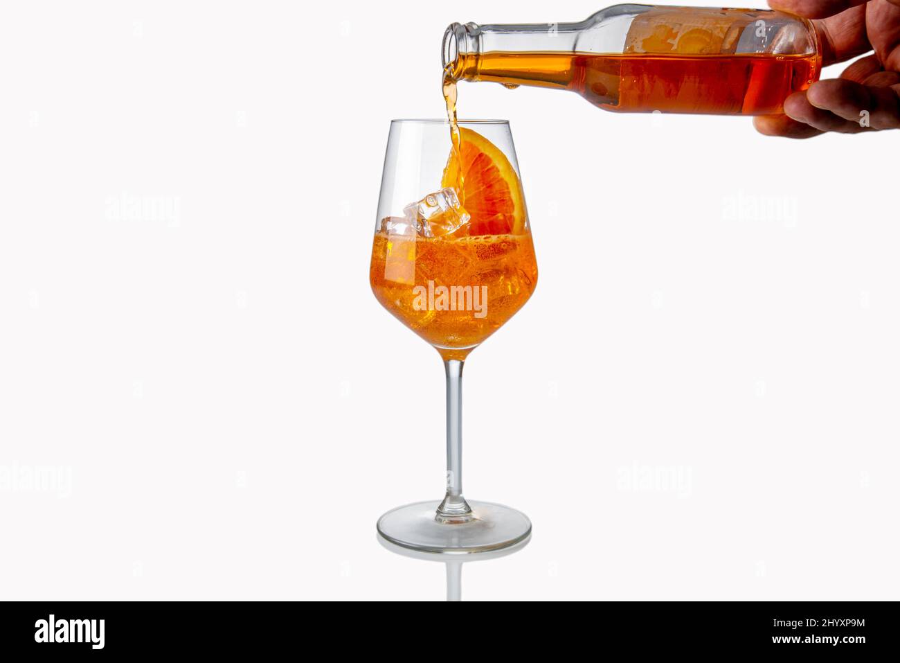 Alkoholischer Aperol Spritz Cocktail aus Glasflasche in Glas gegossen mit Eiswürfel und Orangenscheibe, isoliert auf Weiß Stockfoto