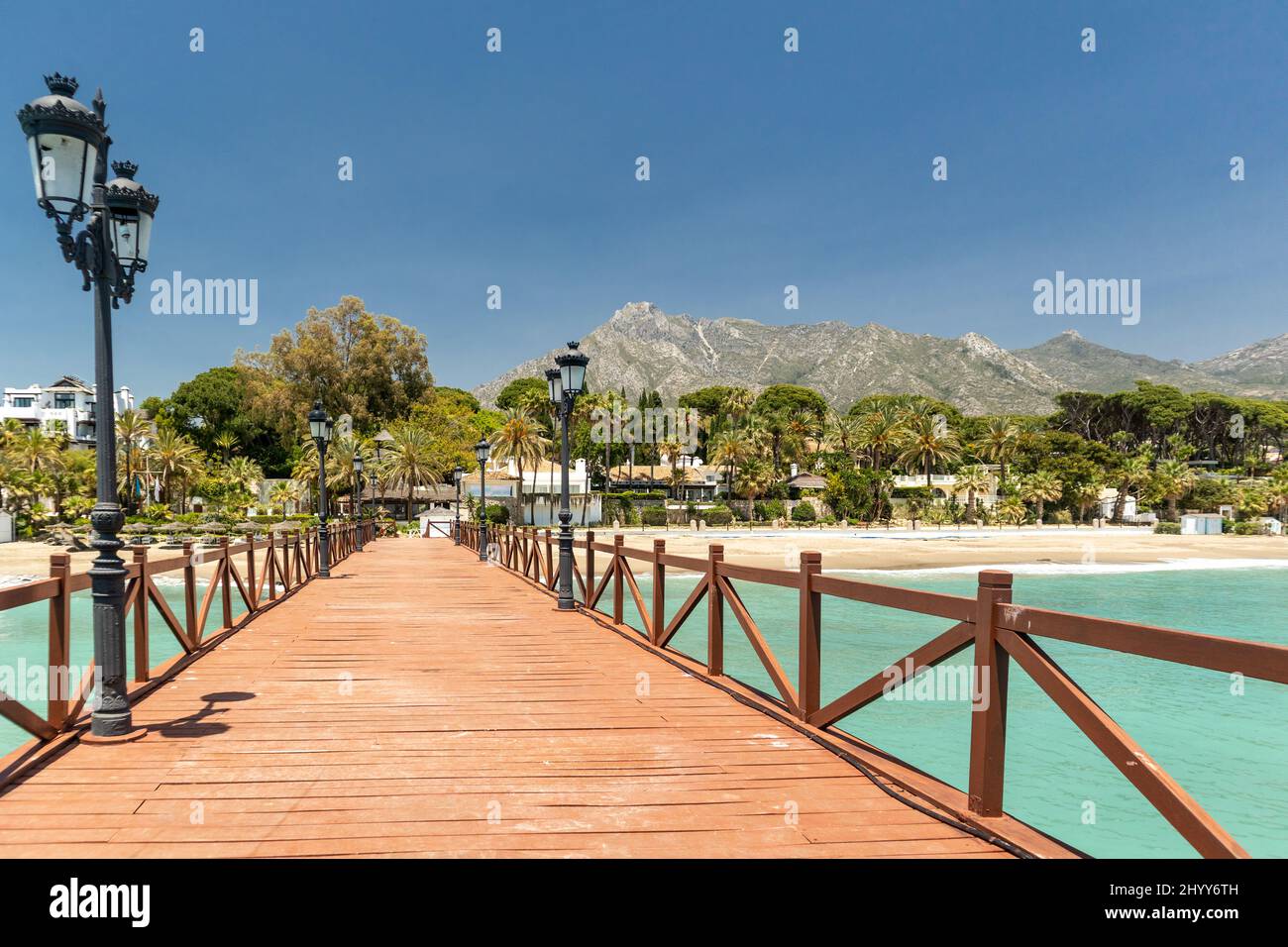 Blick auf die rote Holzbrücke 'Embarcadero' in Marbella. Blick auf das Luxusgebiet Puente Romano, teure Urbanisationen. Berg „La Concha“. Stockfoto