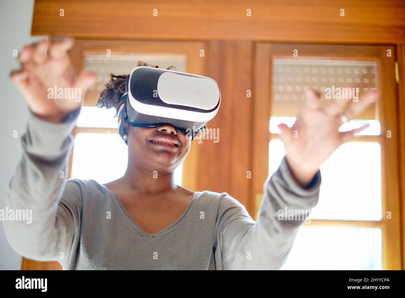 Porträt einer aktiven jungen schwarzen Frau, die einen Virtual-Reality-Simulator in einem Raum zu Hause testet. Technologie- und Lifestyle-Konzepte. Stockfoto