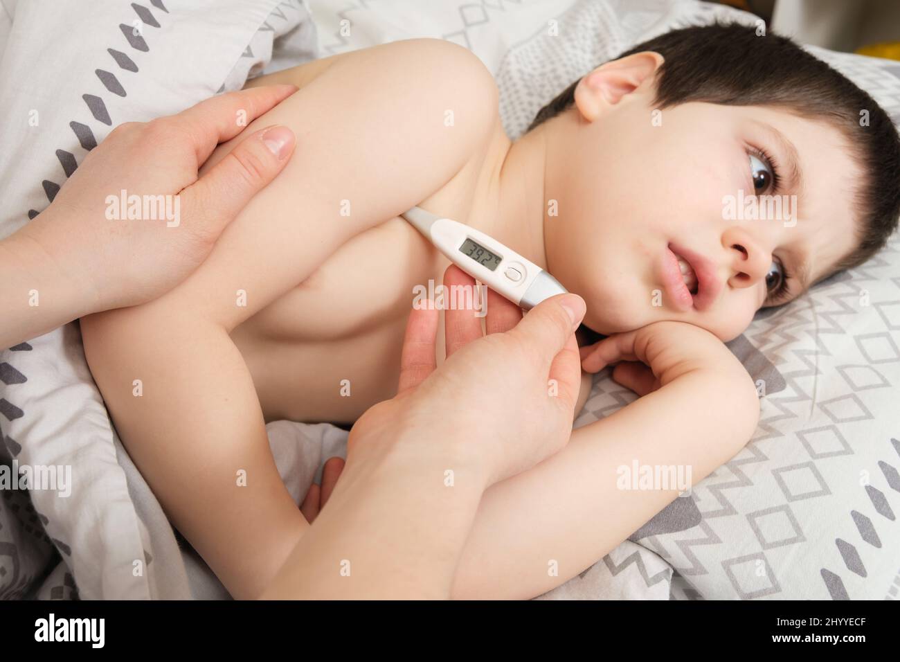 Eine Mutter oder Krankenschwester misst die Temperatur eines 4-jährigen Jungen mit einem elektronischen Thermometer Stockfoto
