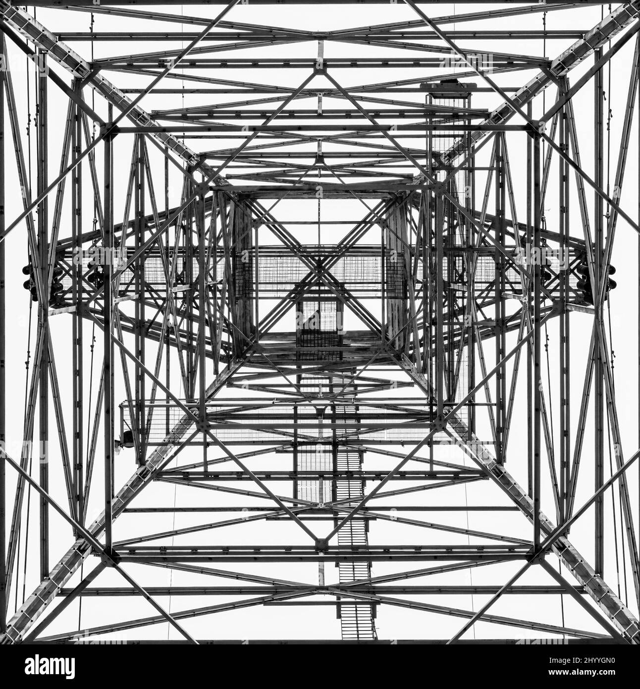 Monochromes Bild eines elektrischen Turms, der nach oben blickt und ein geometrisches, abstraktes Erscheinungsbild verleiht, das einem Testmuster ähnelt Stockfoto
