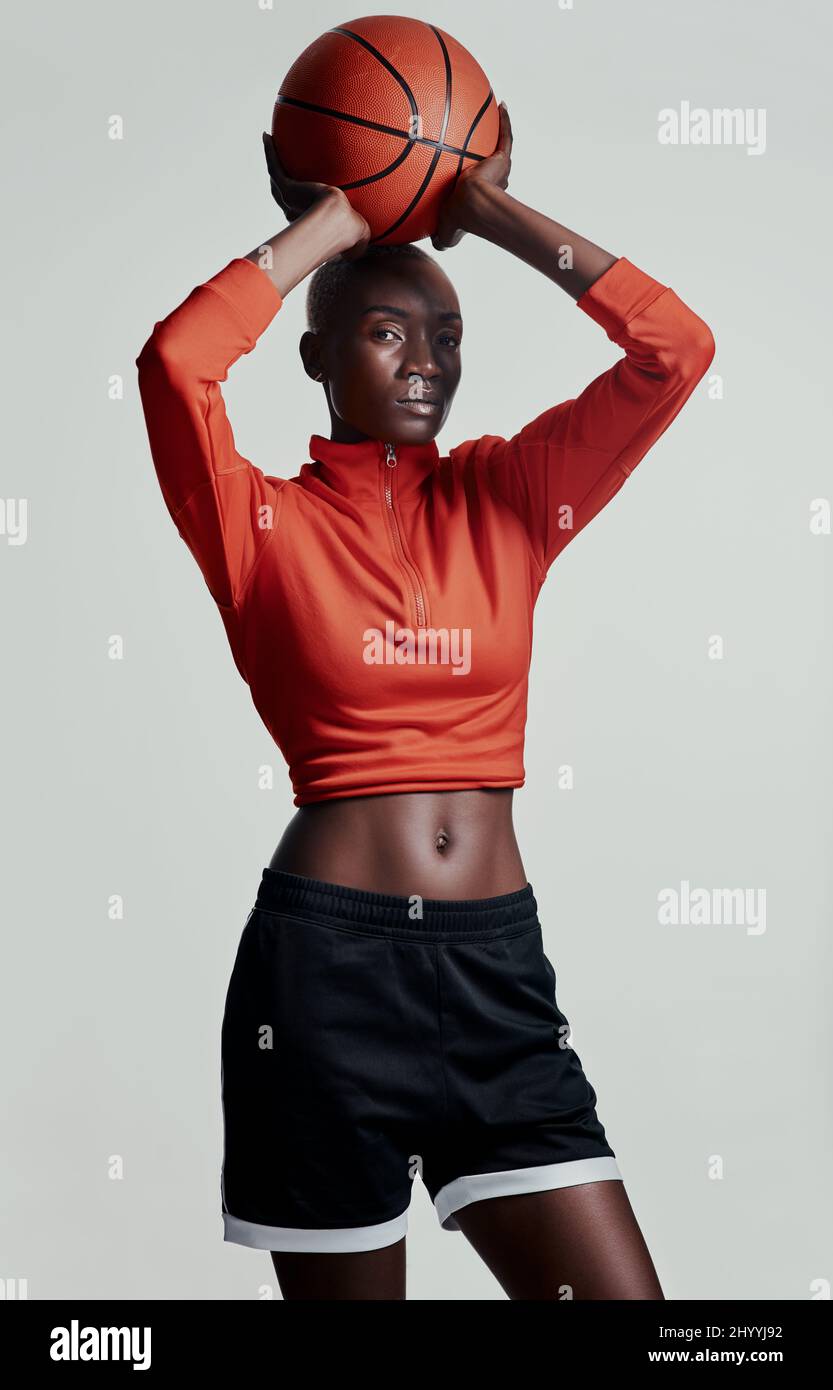 Zielen, schießen, Punkten. Studioaufnahme einer attraktiven jungen Frau, die vor grauem Hintergrund Basketball spielt. Stockfoto