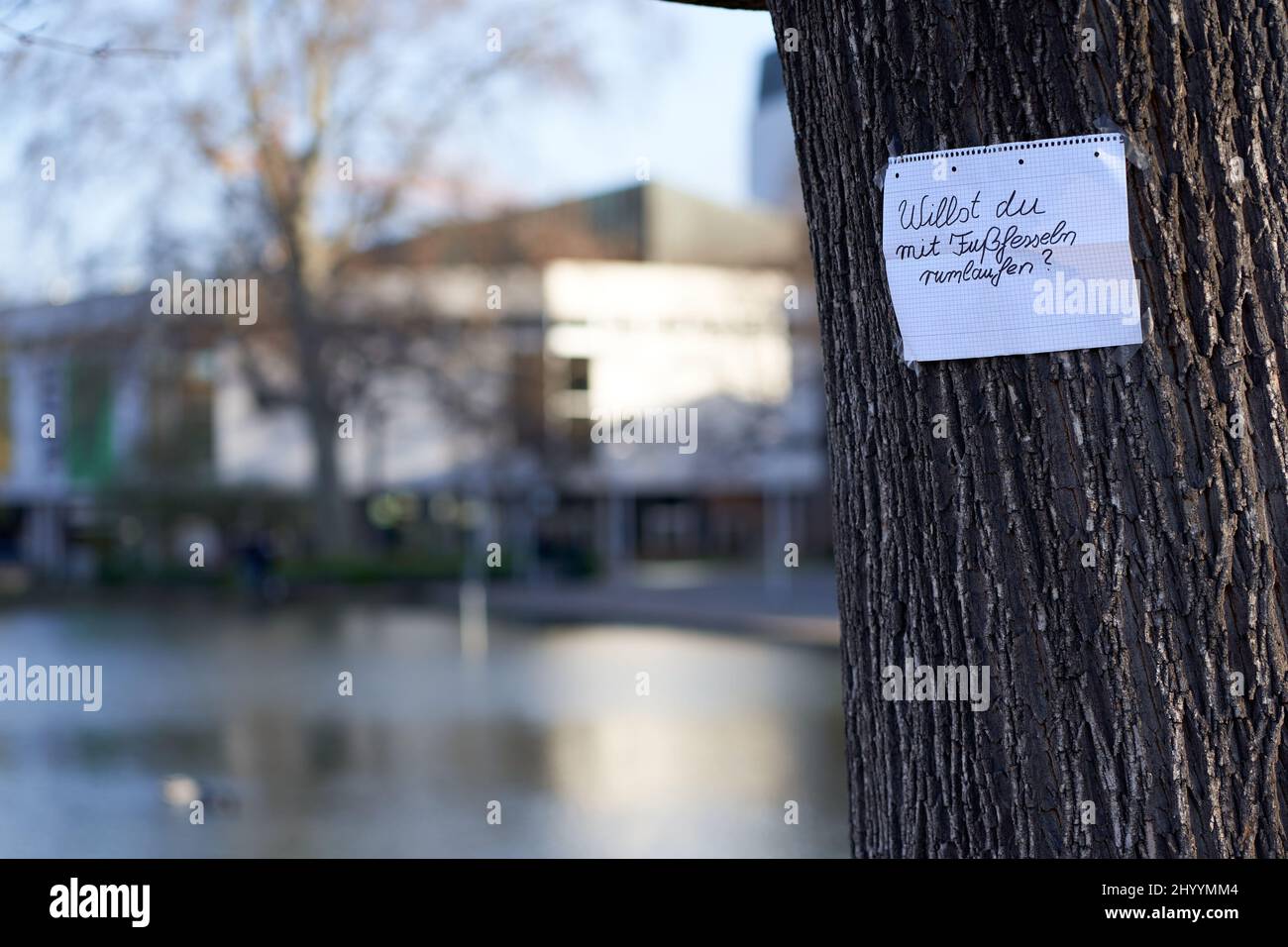 Nachricht von Corona-Gegnern. Weißes Blatt Papier mit schwarzen Buchstaben auf einem Baum in der Stadt. Stockfoto