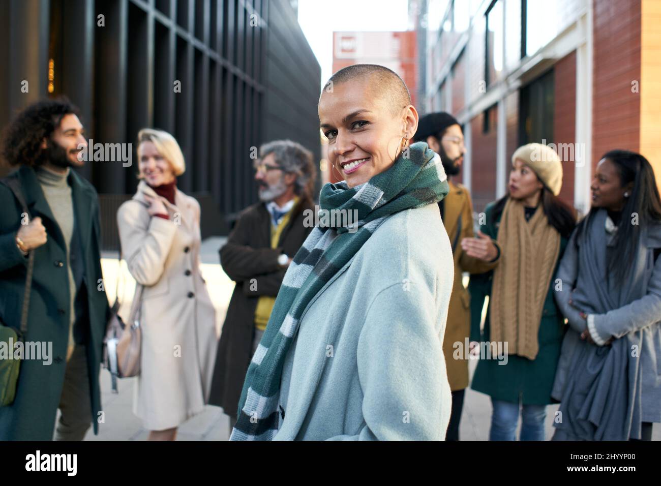 Eine befähigte und selbstbewusste Geschäftsfrau, die durch die Menge der Mitarbeiter im Finanzzentrum lächelnd auf die Kamera blickt. Stockfoto